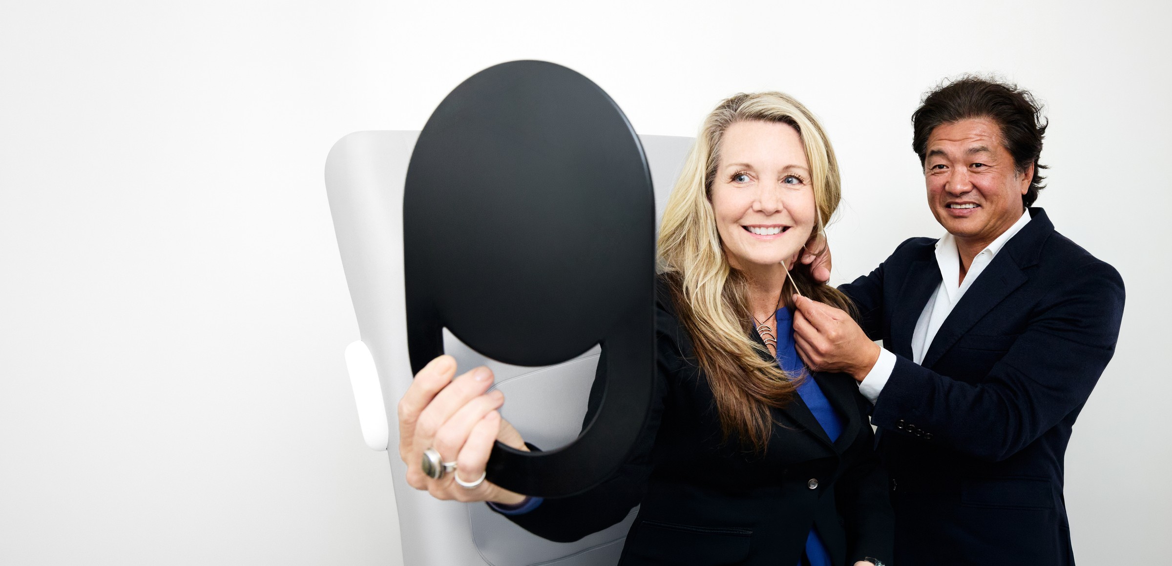 Dr. Min S. Ahn holding a mirror for a smiling patient in the treatment room