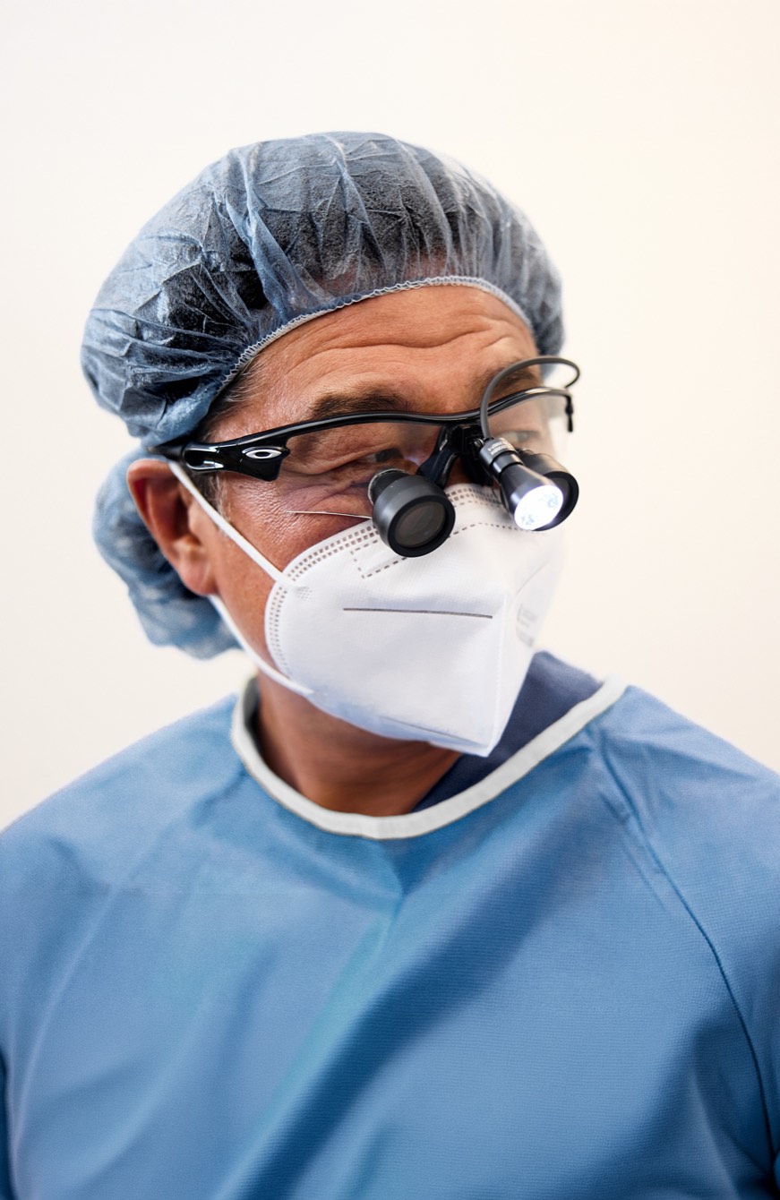 Dr. Min S. Ahn in surgical cap, mask and loupes in the operating room